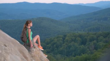 Yürüyüşçü kadın kayalık dağın tepesinde dinleniyor ve vahşi doğa yolculuğunun tadını çıkarıyor. Yüksek tepe yolundan geçen yalnız bir kadın gezgin. Sağlıklı yaşam tarzı kavramı.