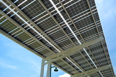 Solar panels installed as shade roof over parking lot for parked electric cars for effective generation of clean electricity. Photovoltaic technology integrated in urban infrastructure.