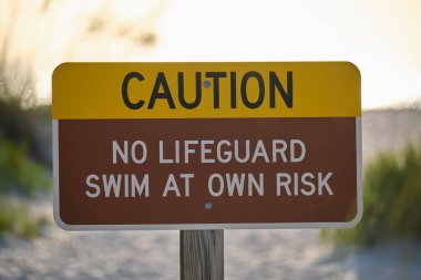 Warning sign poster on sea side beach saying that there is no lifeguard on duty.