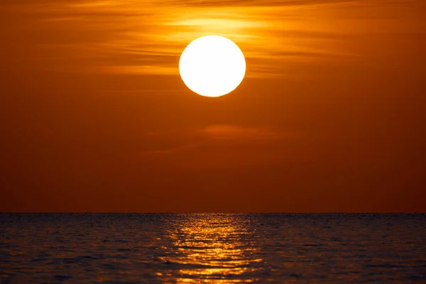 Ocean sunset. Big white sun on dramatic bright sky background, soft evening horizont over sea dark water.