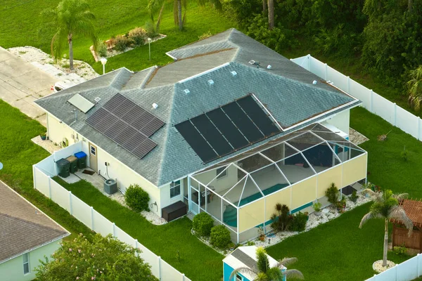 Ordinary residential house in USA with rooftop covered with solar photovoltaic panels for producing of clean ecological electrical energy in suburban rural area. Concept of autonomous home.