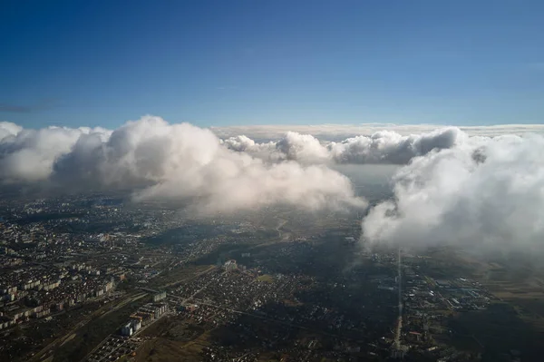暴風雨前に形成されたパフィー積雲に覆われた遠くの都市の高高度での航空機の窓からの眺め — ストック写真