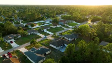Aerial landscape view of suburban private houses between green palm trees in Florida quiet rural area at sunset.