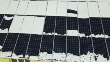 Aerial view of house roof with solar panels covered with snow melting down in winter end for producing clean energy. Concept of low effectivity of renewable electricity in northern region.