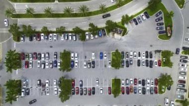 Aerial view of large parking lot with many parked colorful cars. Carpark at supercenter shopping mall with lines and markings for vehicle places and directions.