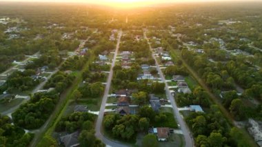 Florida 'daki yeşil palmiye ağaçları arasındaki banliyö özel evlerinin hava manzarası günbatımında sakin kırsal bölge.