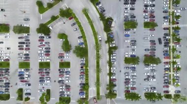Aerial view of large parking lot with many parked colorful cars. Carpark at supercenter shopping mall with lines and markings for vehicle places and directions.