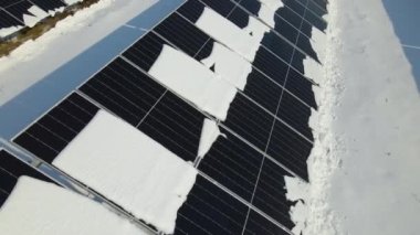 Aerial view of snow melting from covered solar photovoltaic panels at sustainable electric power plant for producing clean electrical energy. Low effectivity of renewable electricity in winter.