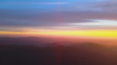 Gün batımında puslu tepeleri ve sisli vadisi olan güzel dağ panoramik manzarası.