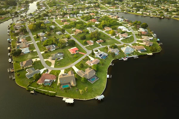 Aerial view of residential suburbs with one storey houses located near wildlife wetlands with green tropical vegetation on sea shore. Living close to nature in warm climate concept.