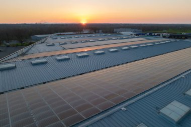 Sanayi binasının çatısına yeşil ekolojik elektrik üretmek için monte edilmiş mavi fotovoltaik panelli güneş enerjisi santralinin hava görüntüsü. Sürdürülebilir enerji konsepti üretimi.