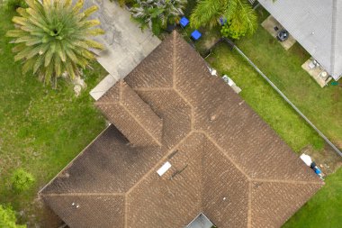 Tipik modern Amerikan özel evinin çatısı asfalt kiremitlerle ve bahçedeki yeşil çimlerle kaplı..