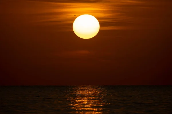 Ocean sunset. Big white sun on dramatic bright sky background, soft evening horizont over sea dark water.