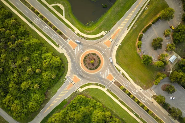 Aerial view of road roundabout intersection with moving cars traffic. Rural circular transportation crossroads.