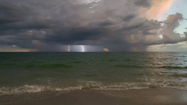 Şiddetli yağış mevsiminde akşam vakti deniz yüzeyinde kasvetli gökyüzünde kara fırtınalı bulutlar oluşur..
