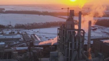 Gün batımında endüstriyel üretim alanında yüksek beton yapılı çimento fabrikası kulesinin havadan görüntüsü. Üretim ve küresel sanayi kavramı.