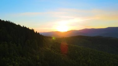 Parlak günbatımında karanlık çam ağaçları olan yüksek tepelerin üzerindeki sisli akşamın havadan görüntüsü. Karanlık çöktüğünde vahşi dağ ormanlarının muhteşem manzarası..