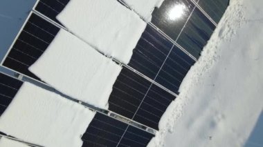 Aerial view of snow melting from covered solar photovoltaic panels at sustainable electric power plant for producing clean electrical energy. Low effectivity of renewable electricity in winter.