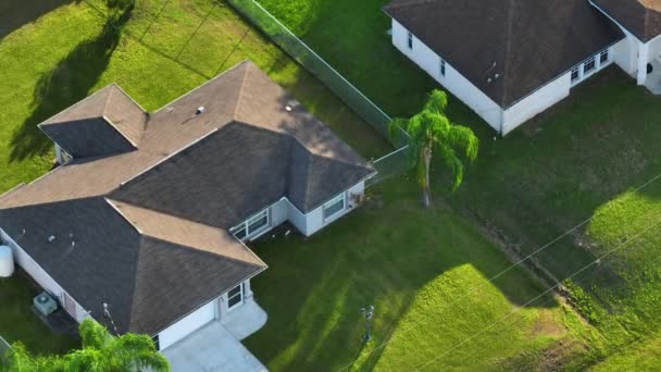 屋根の上にアスファルトの帯状疱疹と庭の緑の芝生で覆われた典型的な現代アメリカの民家の空中ビュー — ストック動画