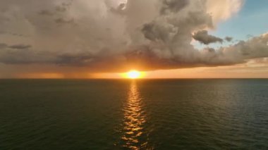 Şiddetli yağış mevsiminde gün batımında okyanus yüzeyinde kara uğursuz fırtına bulutları bulutları oluşuyor..