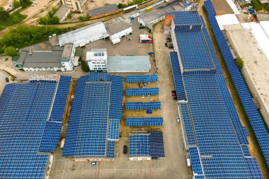 Mavi fotovoltaik güneş panelleri temiz ekolojik elektrik üretmek için endüstriyel binaların çatısına monte edildi. Yenilenebilir enerji konsepti üretimi.