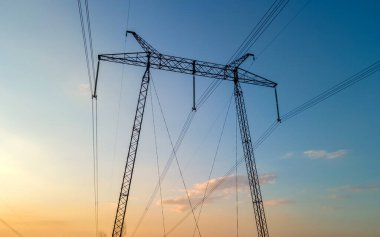 Gün batımında elektrik hatları olan yüksek voltaj kuleleri..