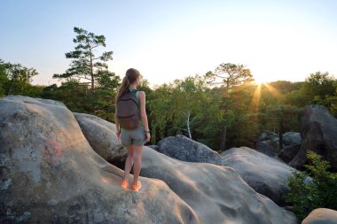 Young woman hiker standing alone on mountain footpath enjoying view of evening nature on wilderness trail. Active way of life concept.
