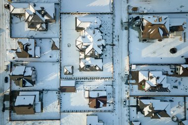 Kışın kırsal kesimde, banliyöde karla kaplı çatıları olan yerleşim yerlerinin hava manzarası..