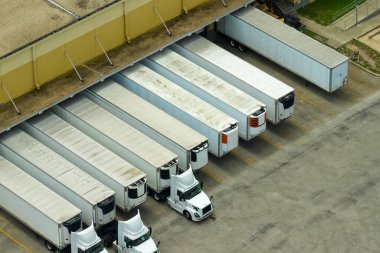 Büyük ticari nakliye merkezinin yüksek açılı görüntüsü. Daha fazla dağıtım için yükleme ve yükleme yapan bir sürü yük kamyonu var. Küresel ekonomi kavramı.