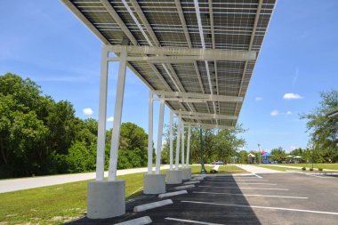 Solar panels installed as shade roof over parking lot for parked electric cars for effective generation of clean electricity. Photovoltaic technology integrated in urban infrastructure.
