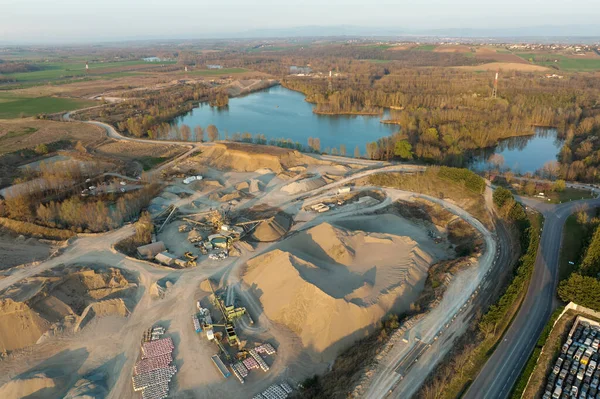 Aerial view of open pit mining site of limestone materials extraction for construction industry with excavators and dump trucks.