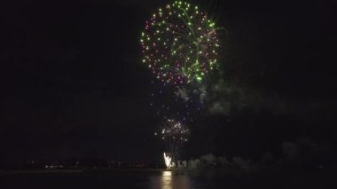 Aerial view of bright fireworks exploding with colorful lights over sea shore on US Independence day holiday.