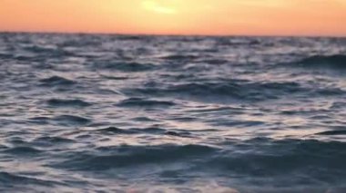 Dramatic red ocean waves at sunset with soft evening sea dark water.