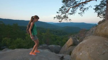 Hiker woman clambering on rocky mountain footpath in evening nature. Lonely female traveler traversing hard wilderness trail. Healthy lifestyle and sport concept.
