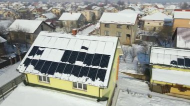 Aerial view of snow melting from covered solar photovoltaic panels installed on house rooftop for producing clean electrical energy. Low effectivity of renewable electricity in nothern region winter.