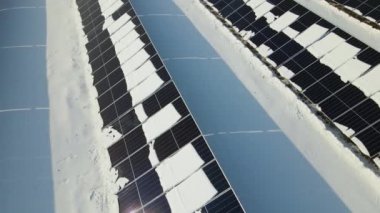 Aerial view of snow melting from covered solar photovoltaic panels at sustainable electric power plant for producing clean electrical energy. Low effectivity of renewable electricity in winter.