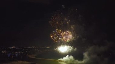 Aerial view of bright fireworks exploding with colorful lights over sea shore on US Independence day holiday.
