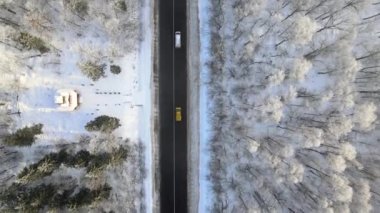 Soğuk kış günlerinde, karla kaplı ormanlar ve siyah asfalt yol manzarası..