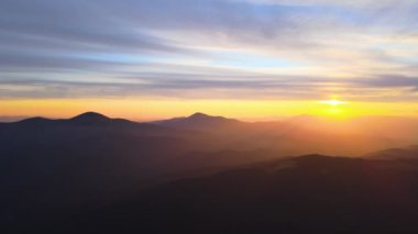 Gün batımında puslu tepeleri ve sisli vadisi olan güzel dağ panoramik manzarası.
