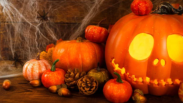 Balkabağı kafalı Jack-o-fener parlayan gözleri ve turuncu sonbahar balkabaklarıyla yakın plan Cadılar Bayramı için sakin bir hayat, arka plan