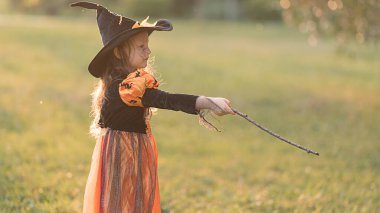 Küçük cadı kız Cadılar Bayramı 'nda sihirli değnekle eğlenir..