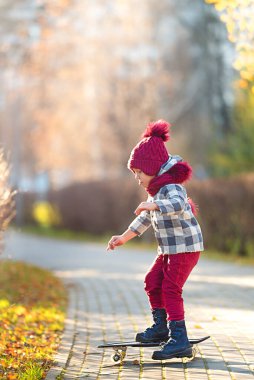 Şehir parkında kaykay süren bir çocuk.