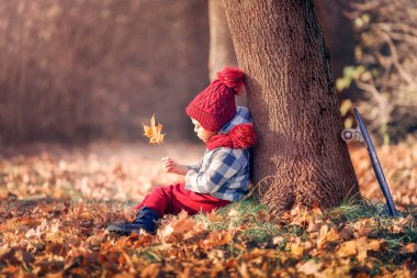 Oğlan sonbaharda parkta üzgün.