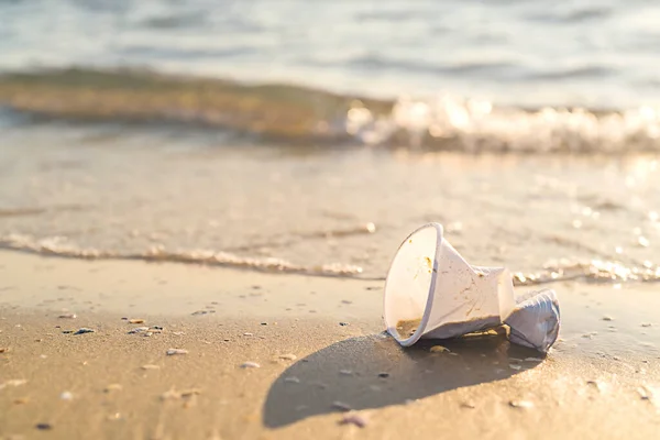 Plastový kelímek ležící na pláži u oceánu — Stock fotografie