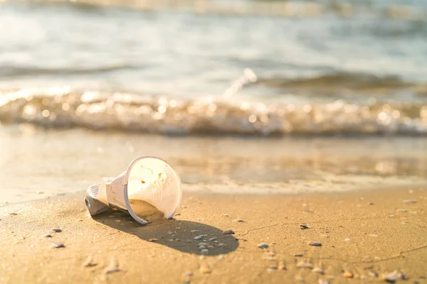Plastový kelímek ležící na pláži u oceánu — Stock fotografie