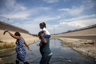 12-30-2021 Haitili adam Rio Grande doğal sınırını geçmek için Meksika ve Amerika Birleşik Devletleri arasında kızını omuzlarında taşıyor.,