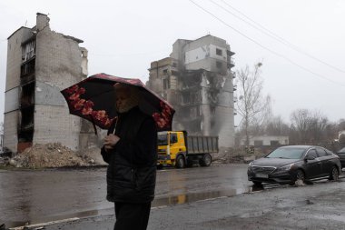 Ukrayna 'daki Rus ordusunun işgali sırasında bir füze tarafından yok edilen binanın önünde yürüyen bir kadın görülüyor.
