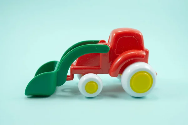 绿松石背景隔离绿色万能刀片红色漆塑玩具推土机 — 图库照片
