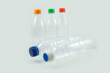 Kullanılmış plastik şişelerin geri dönüşüm için yakın plan beyaz arka planda izole edilmiş renkli şişe kapakları.