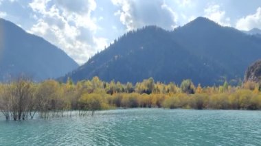 Eylül 'de sonbaharda dağ gölü, turkuaz su. Güneş ışınları suyun üzerinde parlıyor. Dağların arka planına karşı göl. Issyk Gölü, Kazakistan 4k video